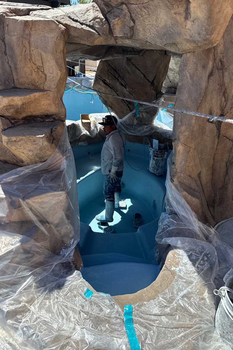 Large stones are visible next to a swimming pool that is currently being painted