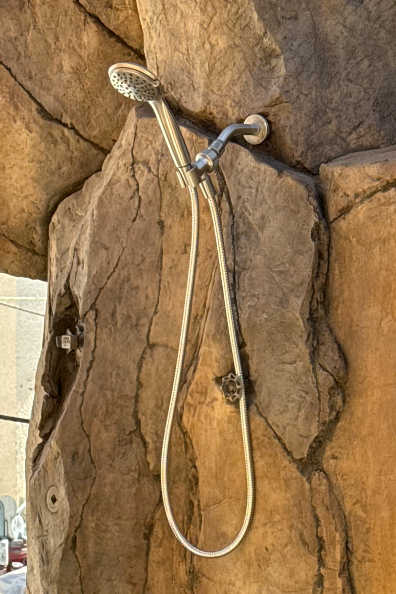 A shower area seamlessly integrated and built into a wall or structure made of large, natural stones.