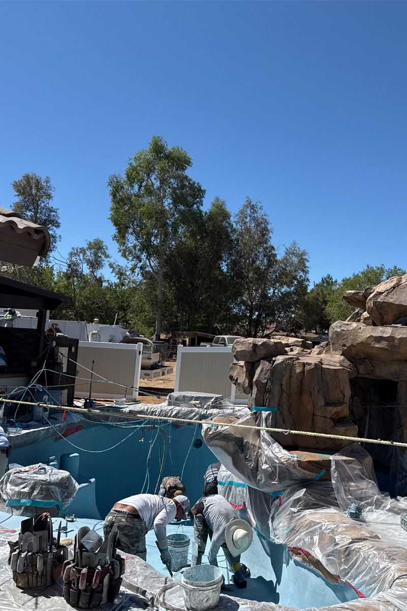 Workers are applying the final touches of paint to a swimming pool.