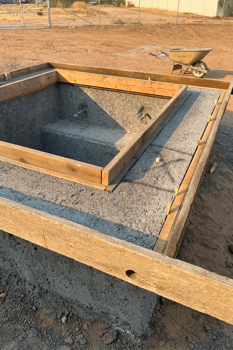 A fireplace currently in the process of being built A composition or scene featuring both cement and wood materials.