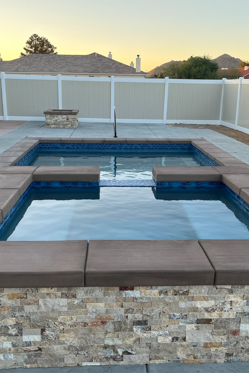 A blue swimming pool with an integrated jacuzzi, surrounded by walls in beige and white colors.