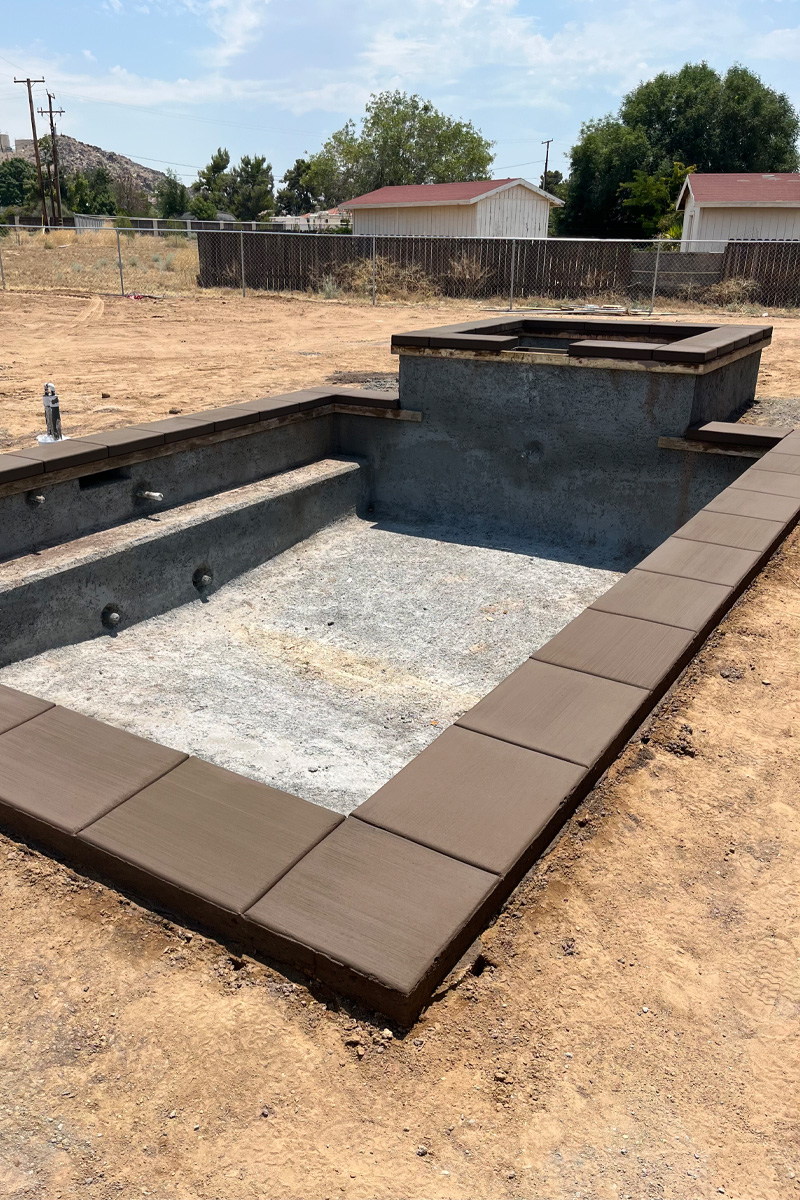 A swimming pool currently under construction, with fresh cement that has a brown tint.