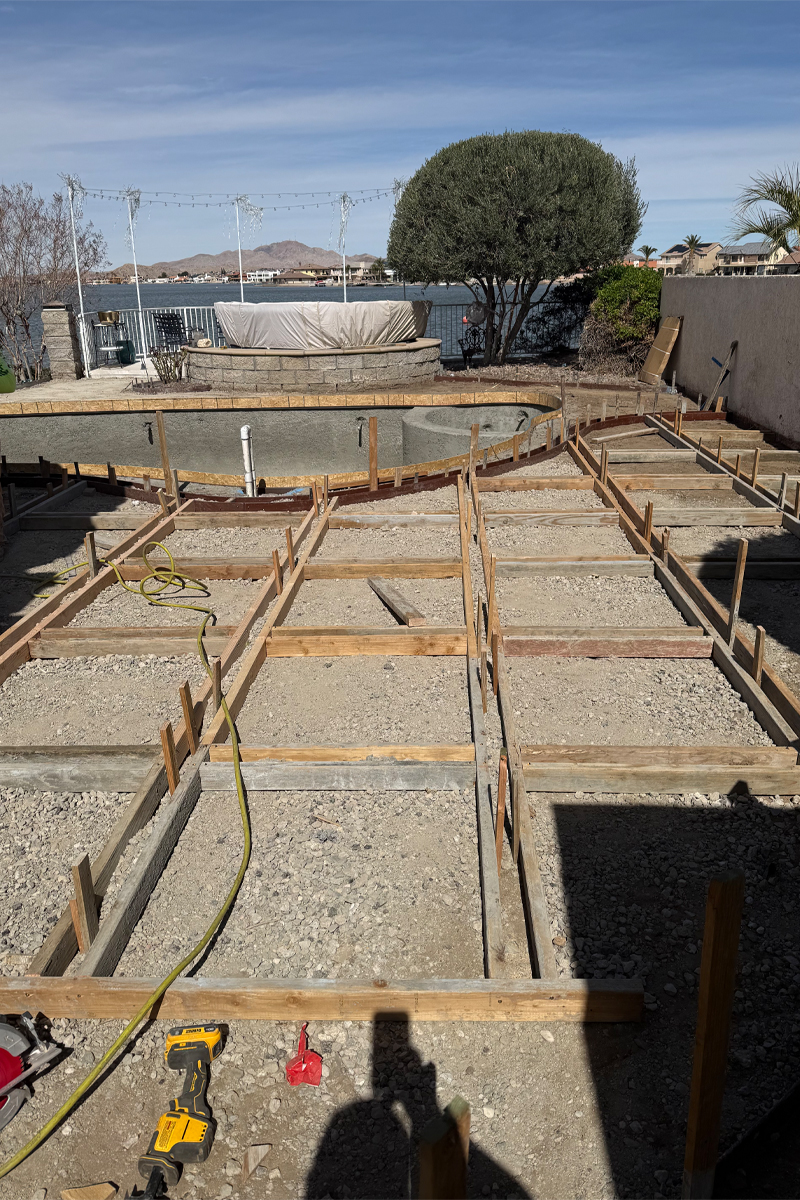 A swimming pool and patio area currently under construction, with  wooden structural frameworks visible.

