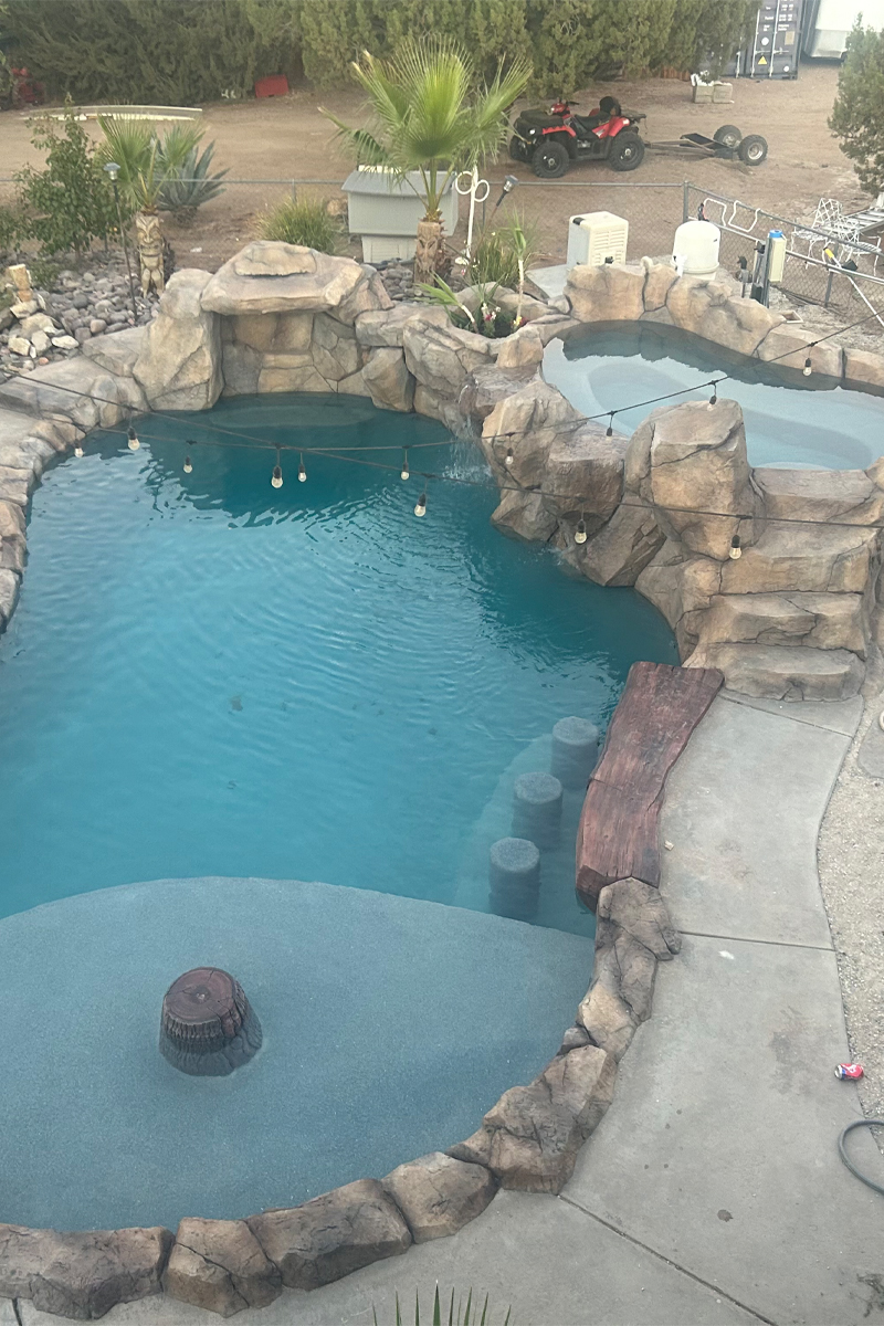 A stunning swimming pool with sparkling  light blue water, constructed from natural stones and featuring an integrated jacuzzi.