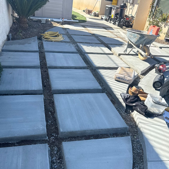 Square sections of cement are being laid out for a patio, currently in the process of construction.