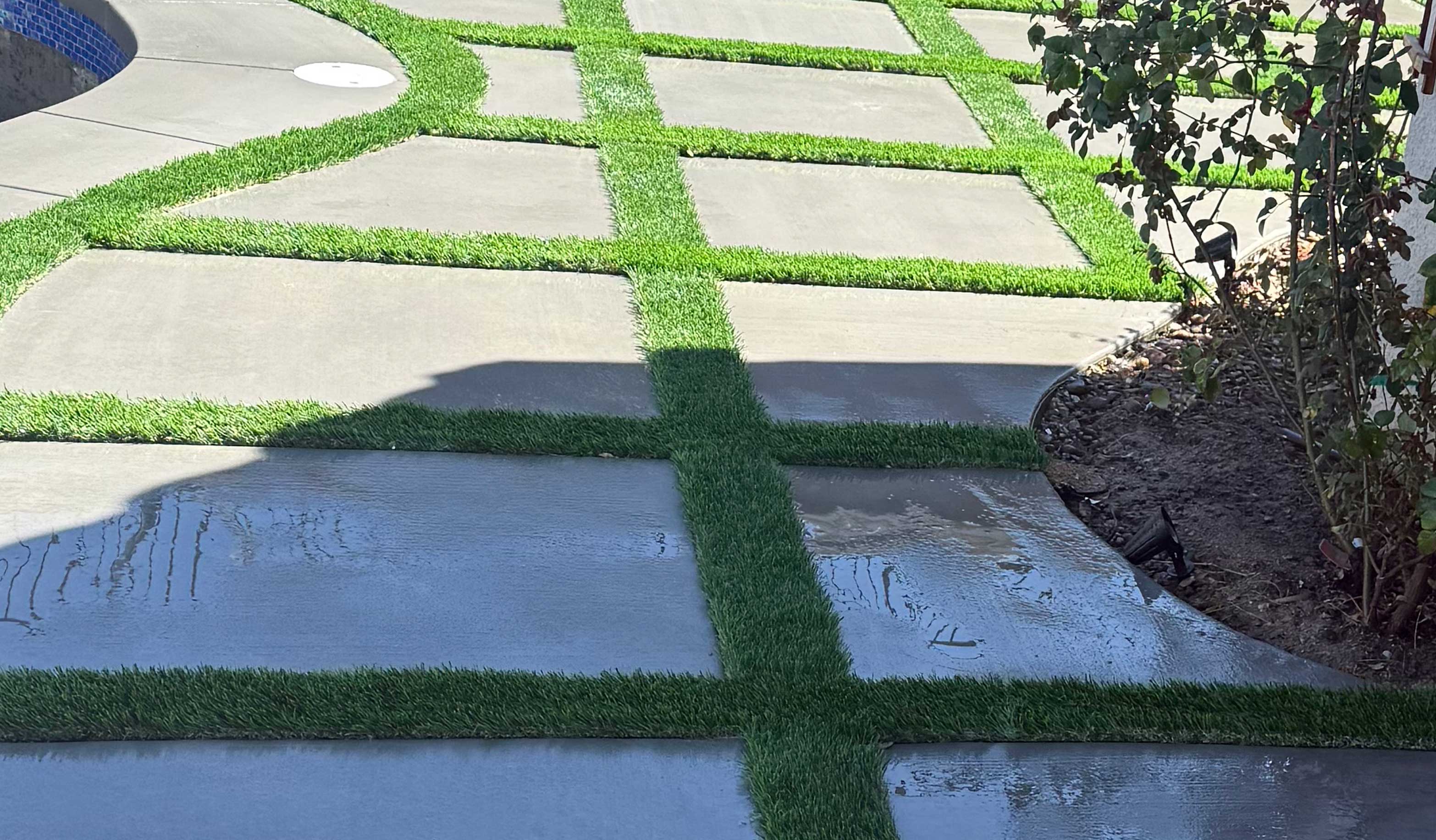 A fresh and modern cement patio featuring clean lines of artificial grass integrated into its design.