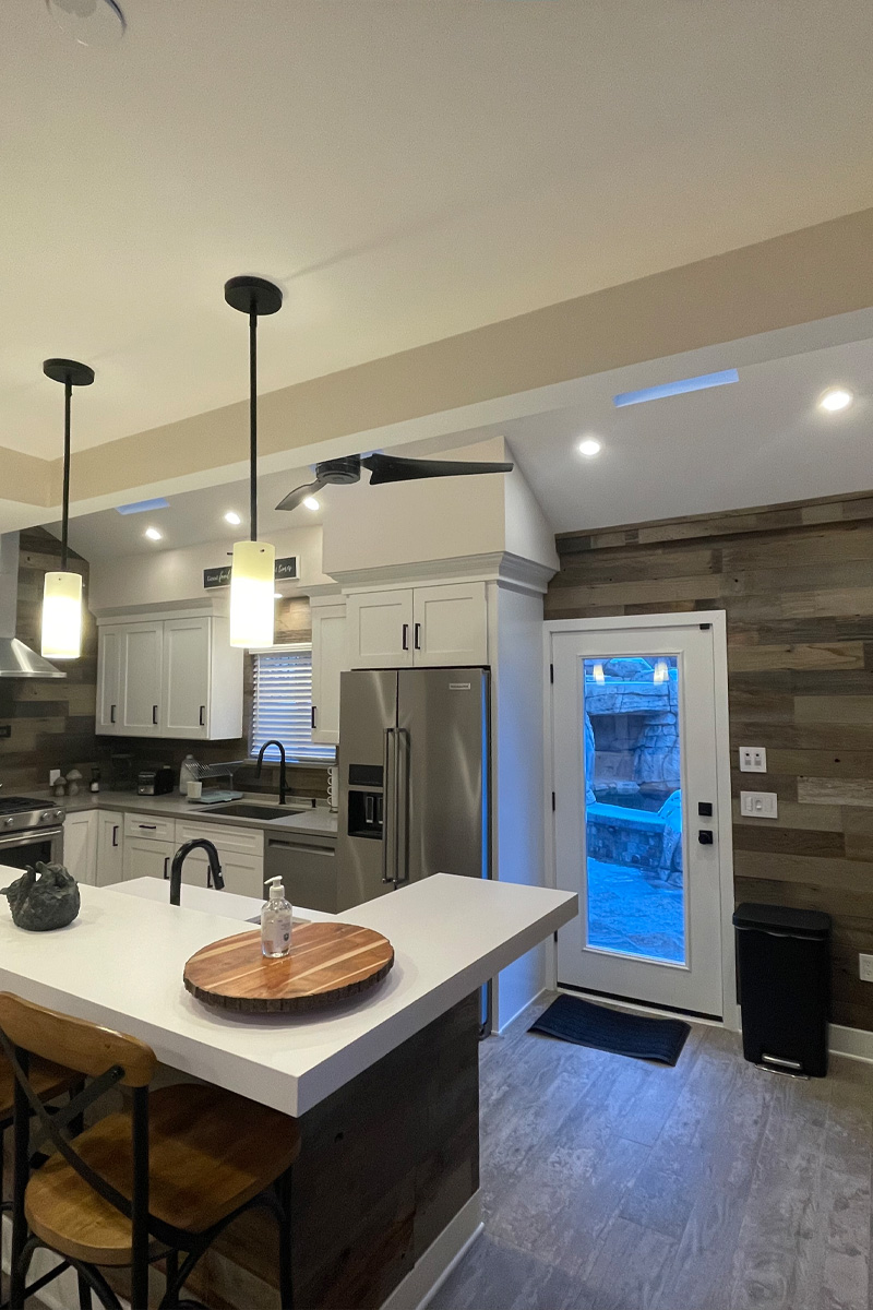 A beautiful kitchen with pristine white cabinets and stylish pendant lights hanging over the counter. A door provides convenient access directly to the patio.