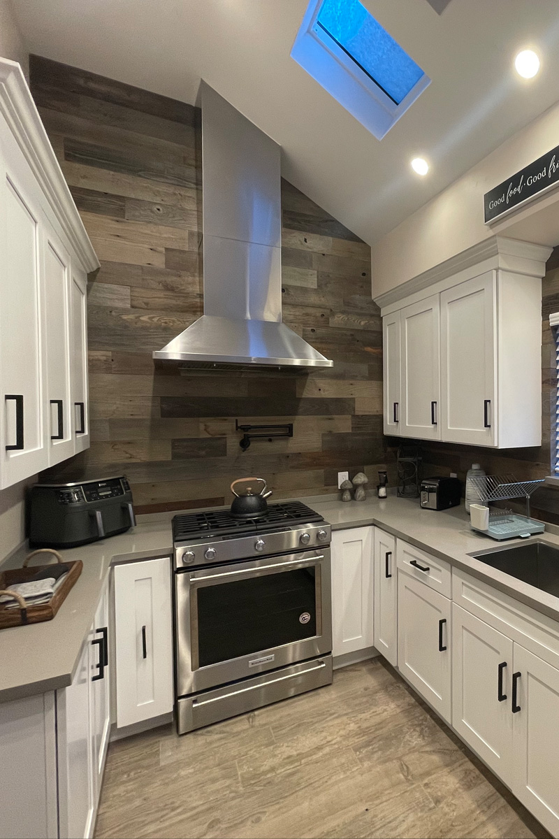 A luxurious kitchen featuring a stove and range hood made of stainless steel. The kitchen is outfitted with elegant white cabinets.