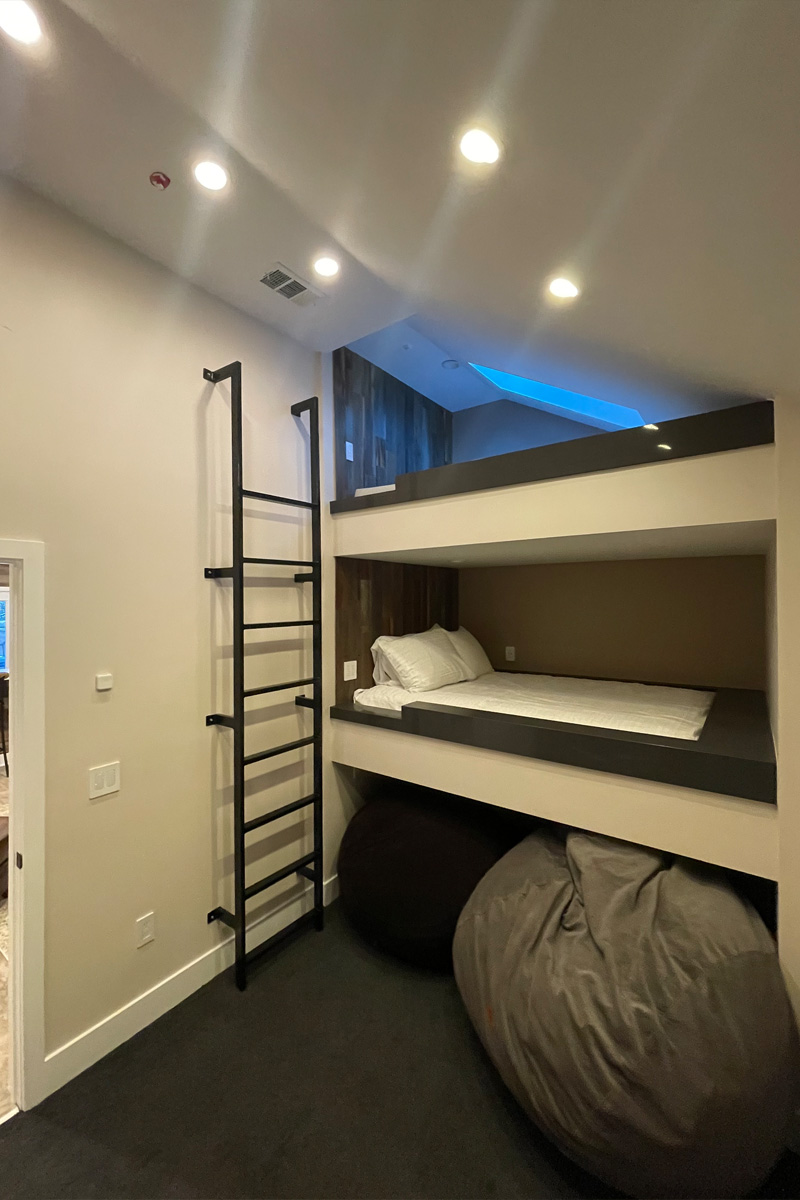 A room featuring a unique bunk bed constructed from concrete. The structure is integrated into the wall, and the stairs leading to the top bunk are built directly into the wall itself.