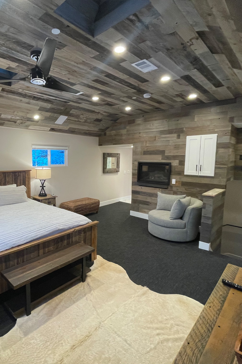 An elegant bedroom featuring a sophisticated grey wooden ceiling. The room is furnished with a stylish wooden bed and A grey sofa is placed in the corner of the room.