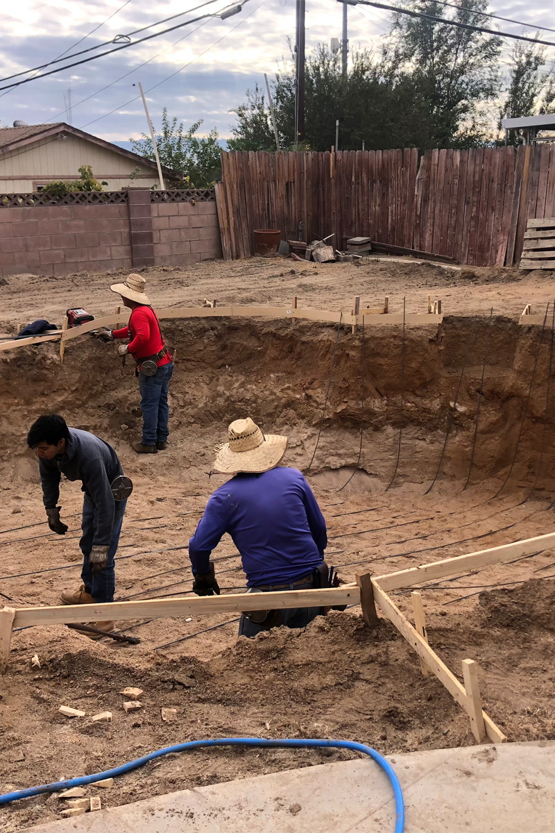 men are working on the construction of an in-ground swimming pool