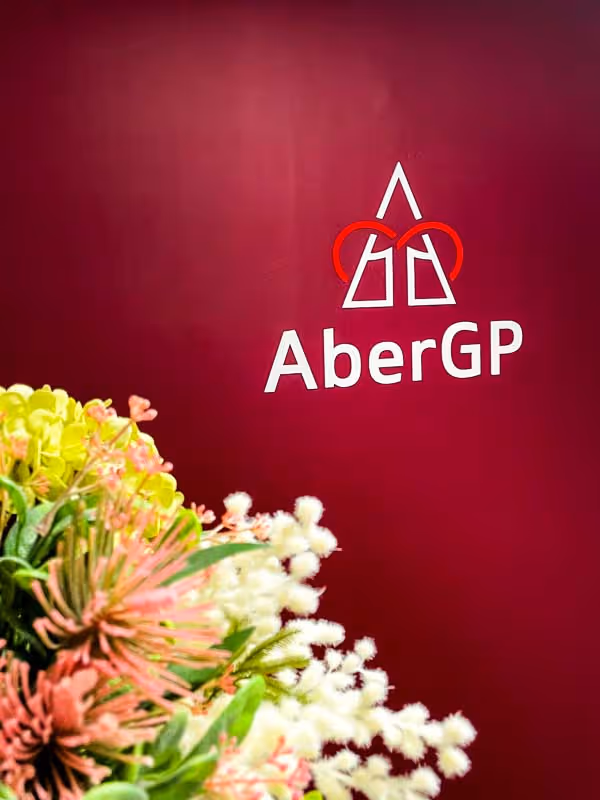 AberGP logo on a burgundy wall with a bouquet of mixed flowers in the foreground.