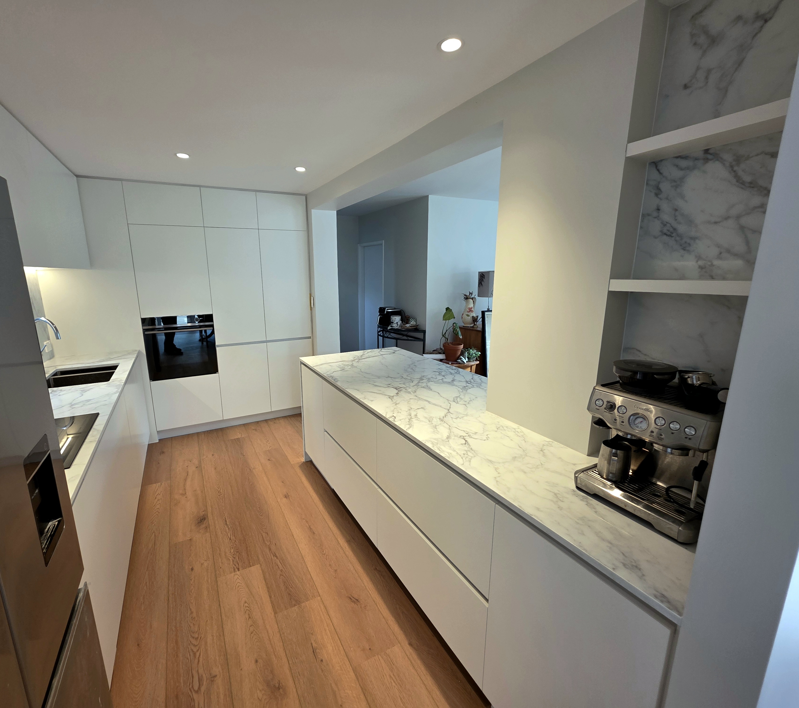 Galley-style kitchen with marble benchtop island and oak flooring