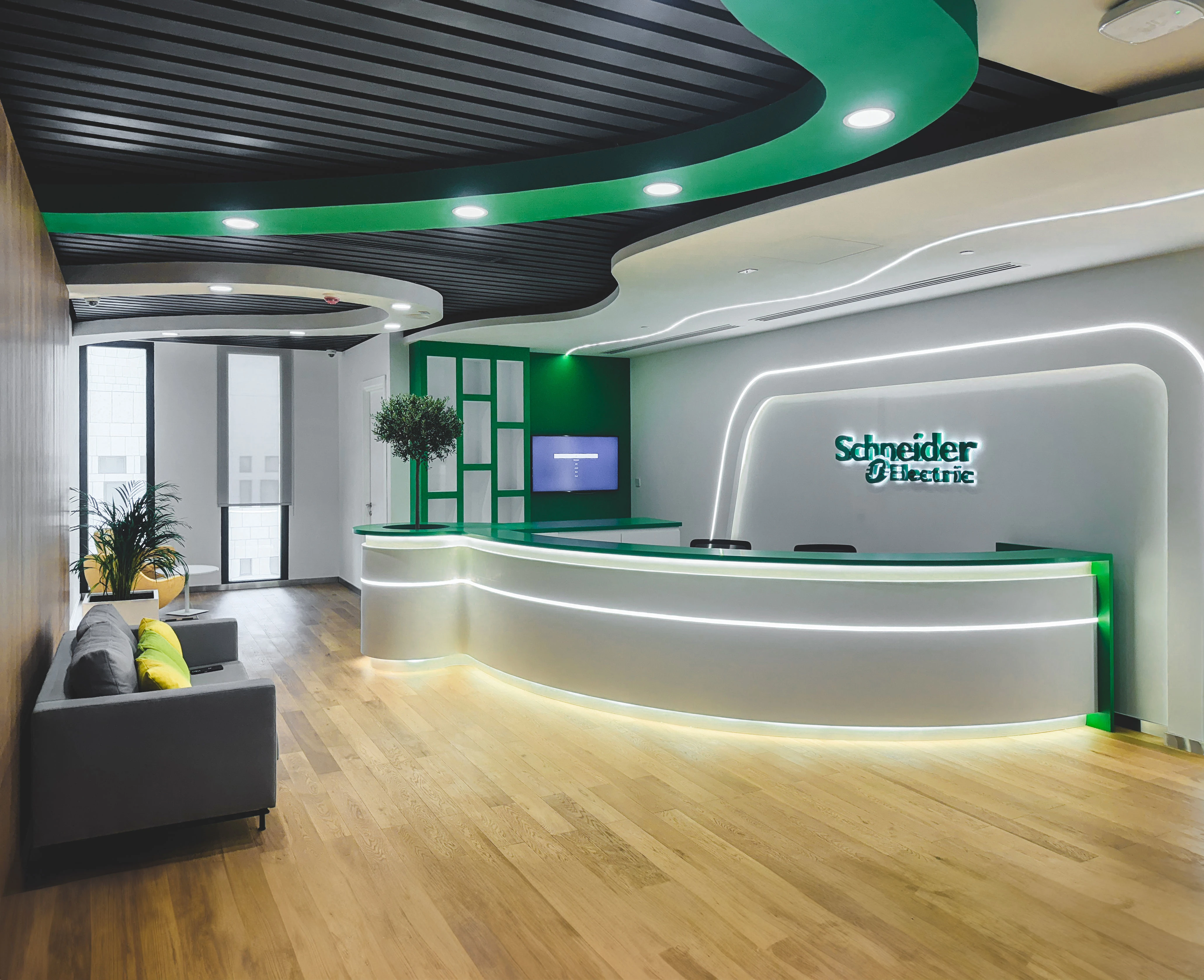 Schneider Electric reception desk with illuminated logo signage, Msheireb, Doha, by Daya