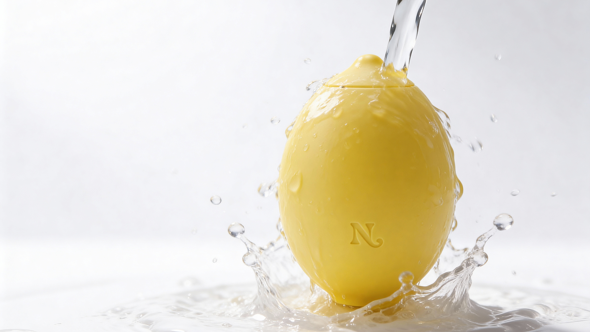 Yellow Lem clitoral massager in a studio water splash