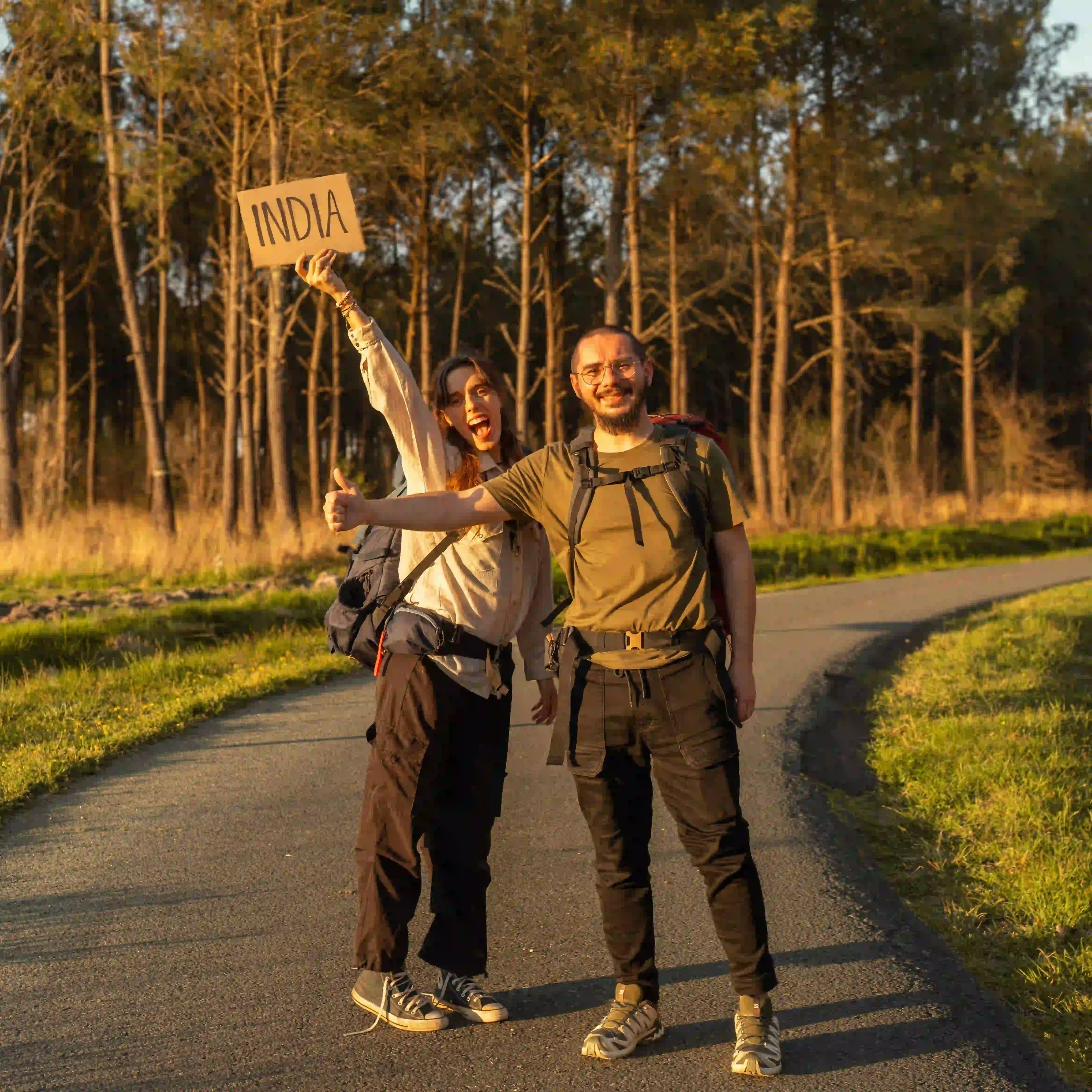 Mathilde Odile et Arnaud font du stop, tenant dans les mains une pancarte India