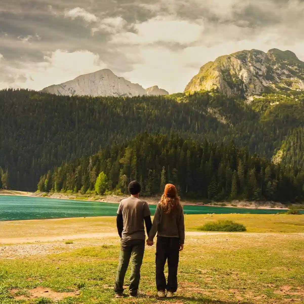 Mathilde Odile et Arnaud se tiennent la main devant un lac et une forêt