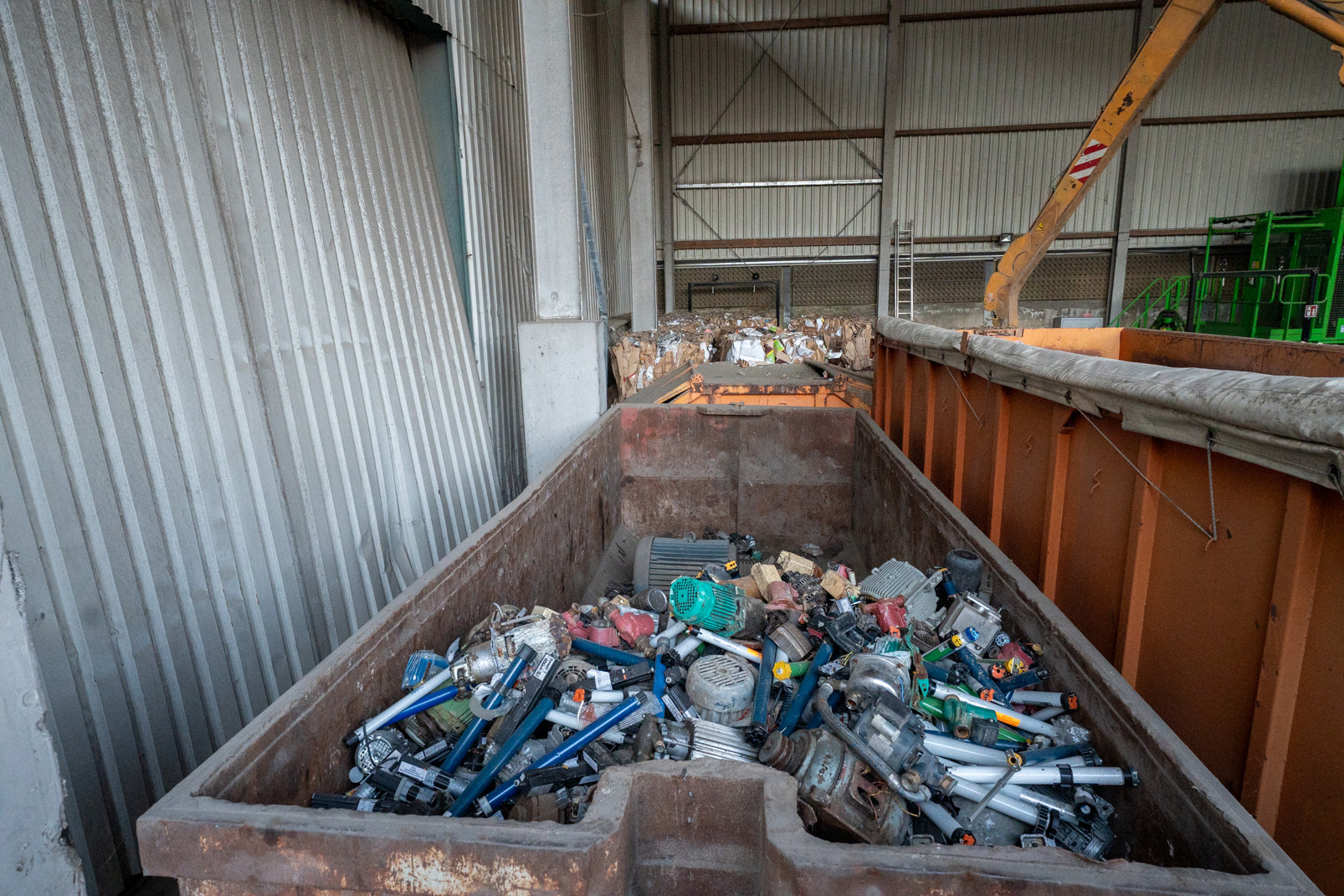 Großer Behälter in einer Halle gefüllt mit verschiedenen alten Elektromotoren und mechanischen Teilen.