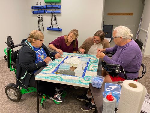 Two DNEM staff and two Consumers complete mosaic mirror for Art from the Heart event