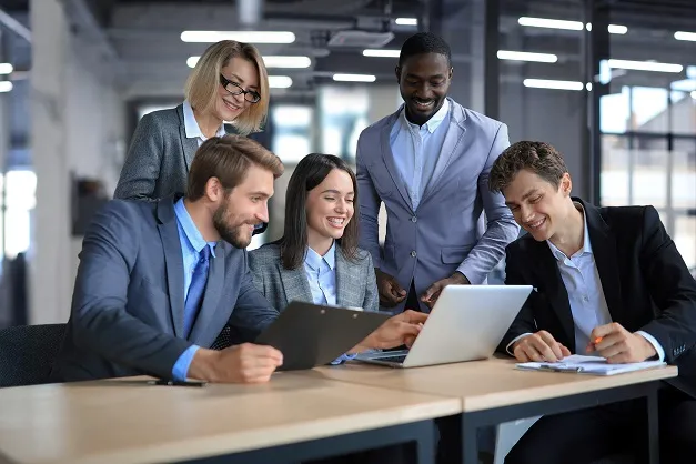 Groupe de professionnels souriants autour d'un ordinateur portable