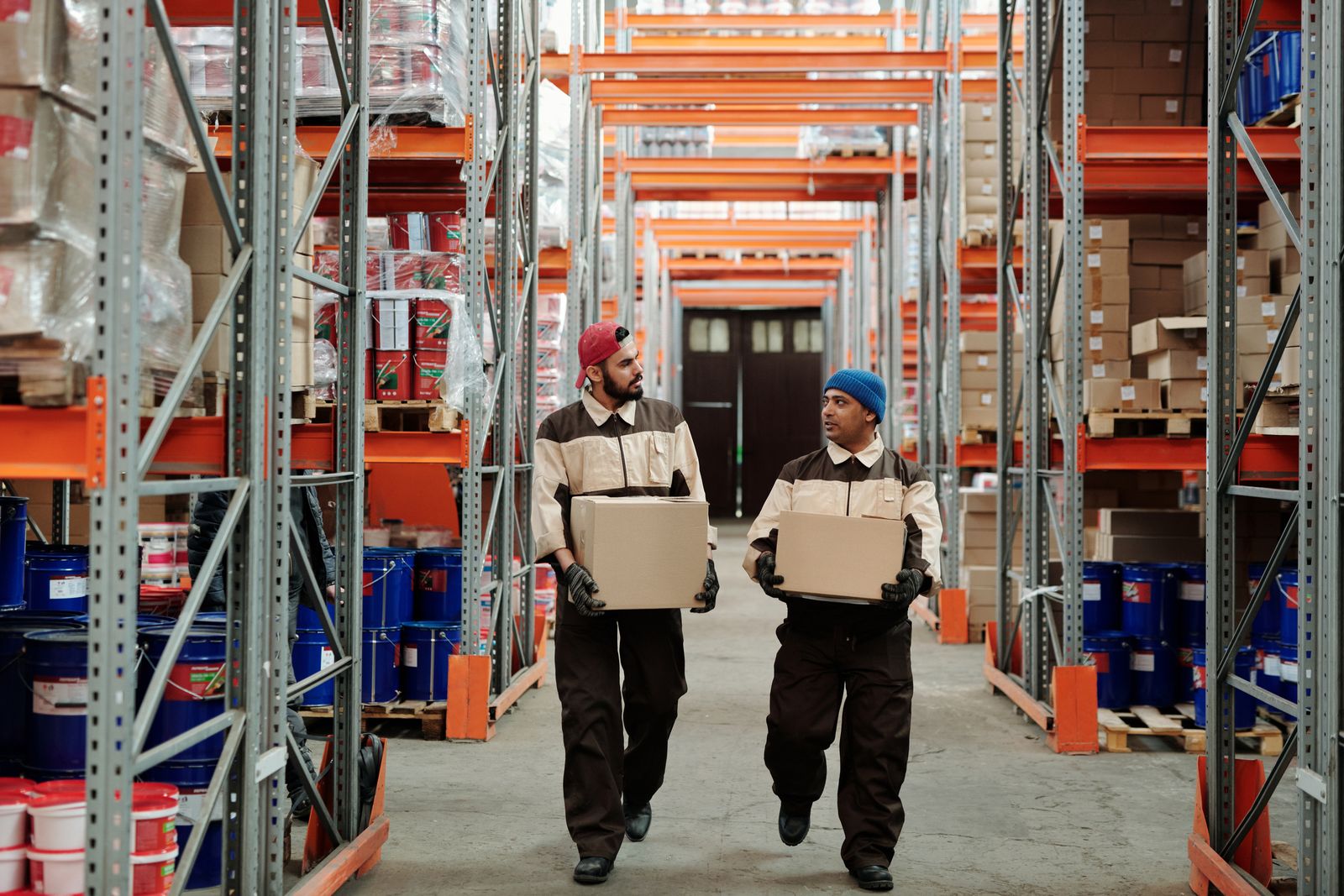 Deux salariés transportent des cartons dans l'allée d'un entrepôt de logistique