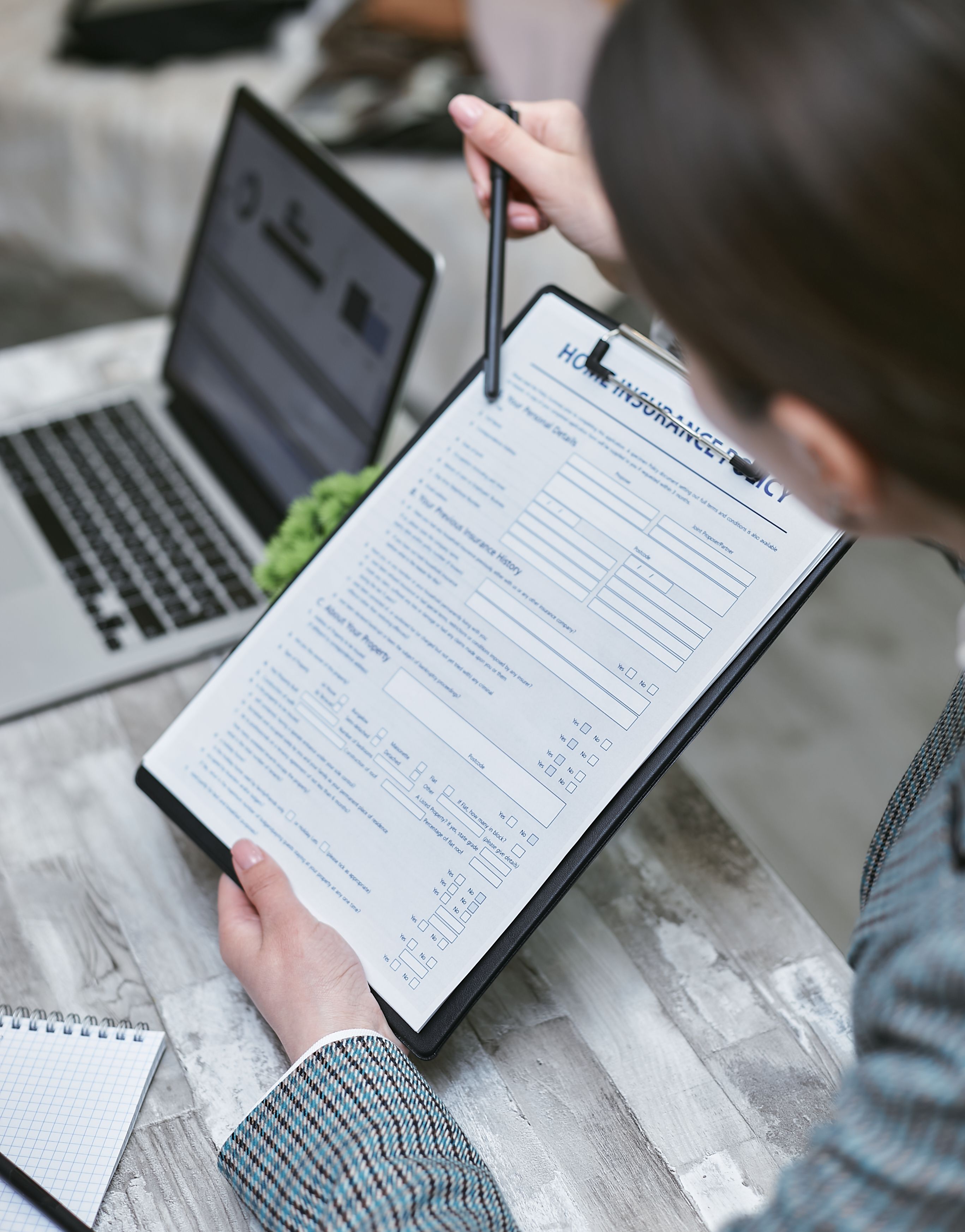 Une personne relit un document imprimé, stylo en main, à côté d'un ordinateur portable