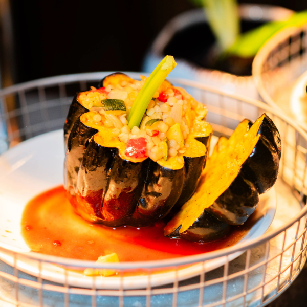 Acorn squash stuffed with rice and vegetables served with sauce on a white plate.