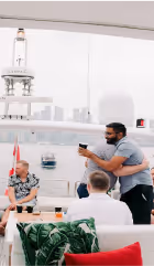Man serves a cup of coffee to seated people in a bright cafe with modern decor.