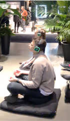 Three people seated on cushions indoors, meditating or practicing mindfulness.
