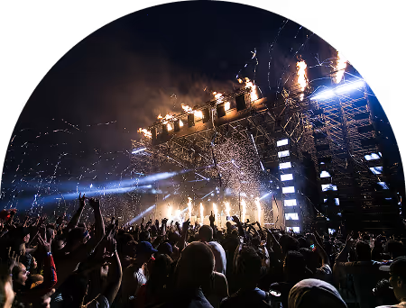 Crowd at a nighttime concert with stage lights and fireworks.
