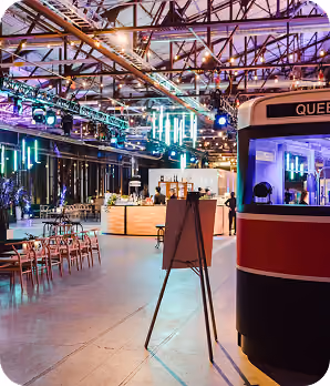 Spacious event hall with colorful lighting, chairs, bar area, and partial view of a tram car.