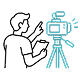 Person behind a video camera on tripod recording or filming.