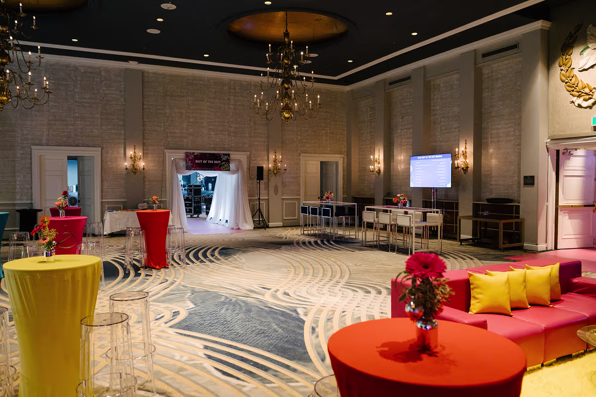 Elegant event room with colorful cocktail tables, floral arrangements, red couches, and Art of the Party entrance