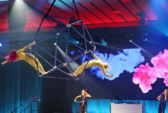 Aerial performance rigged from the ceiling, programmed against live strings so the room has two focal points rather than one.