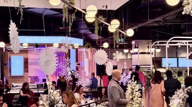 Flocked trees, paper snowflakes and a live string trio turn a food hall into a winter holiday room. The best corporate Christmas party ideas give guests something to do, keep the formal parts