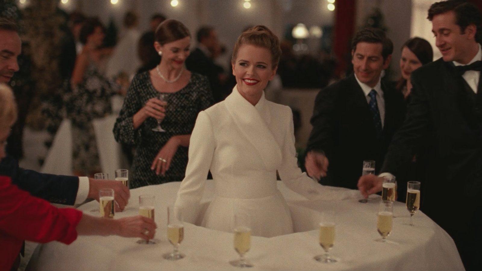 Server in a white winter gown whose skirt holds champagne flutes for guests
