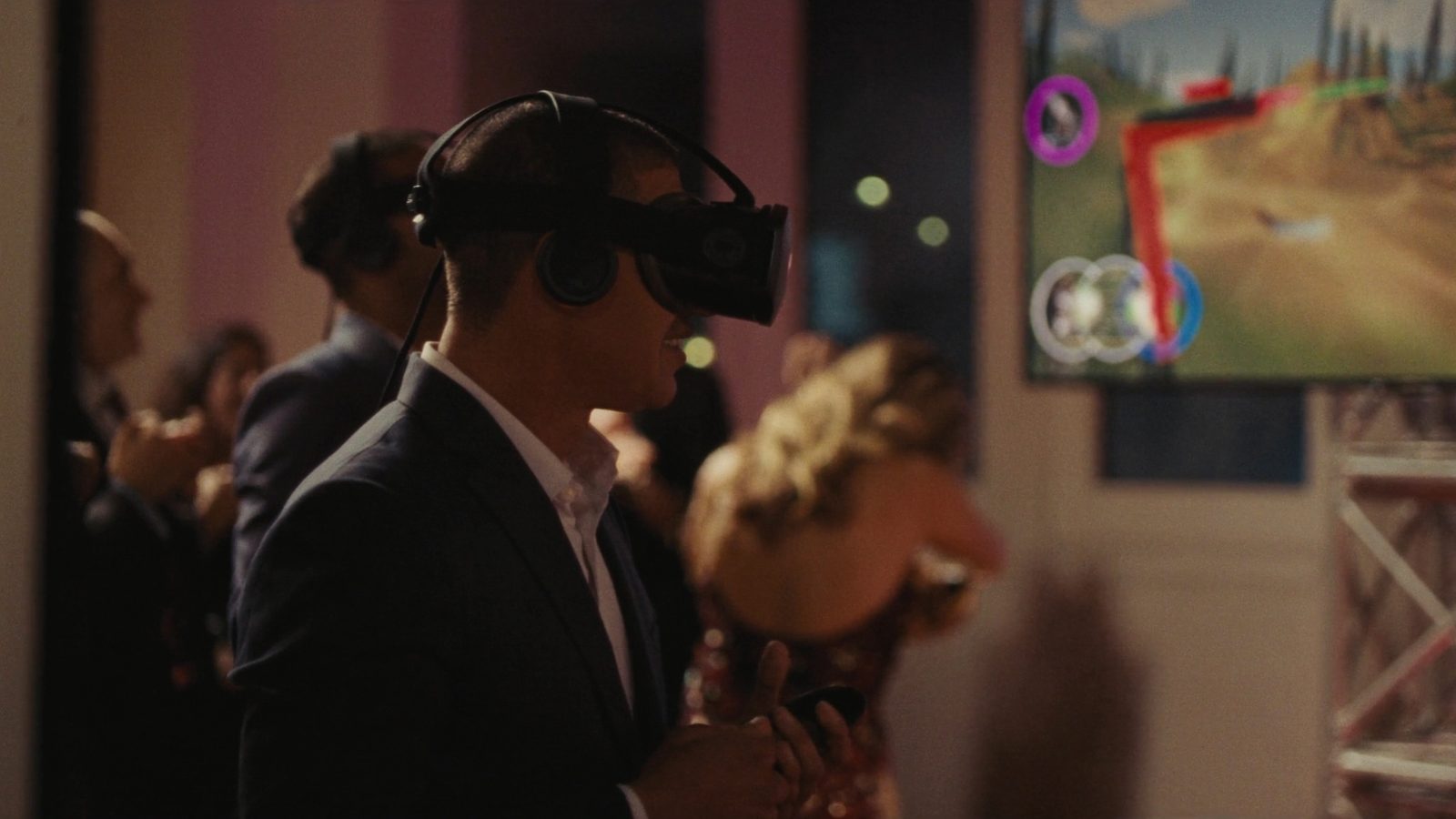 Guests playing a virtual reality game at a VR station beside a large screen