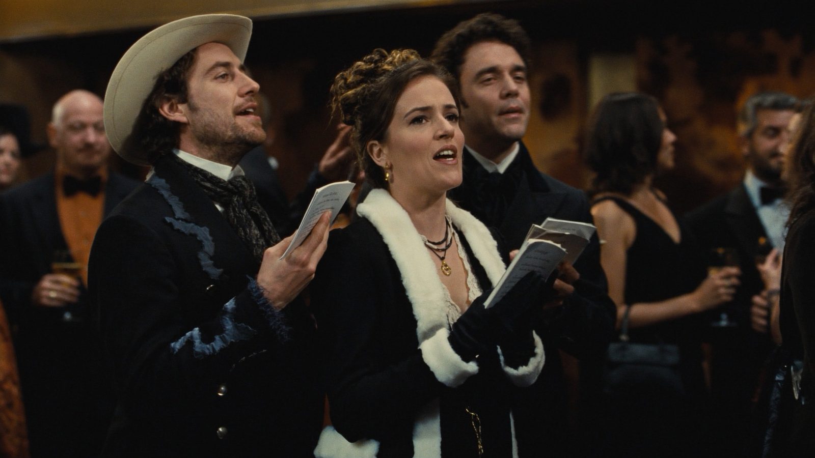 Holiday carolers in Victorian winter costumes singing from songbooks at a corporate holiday party