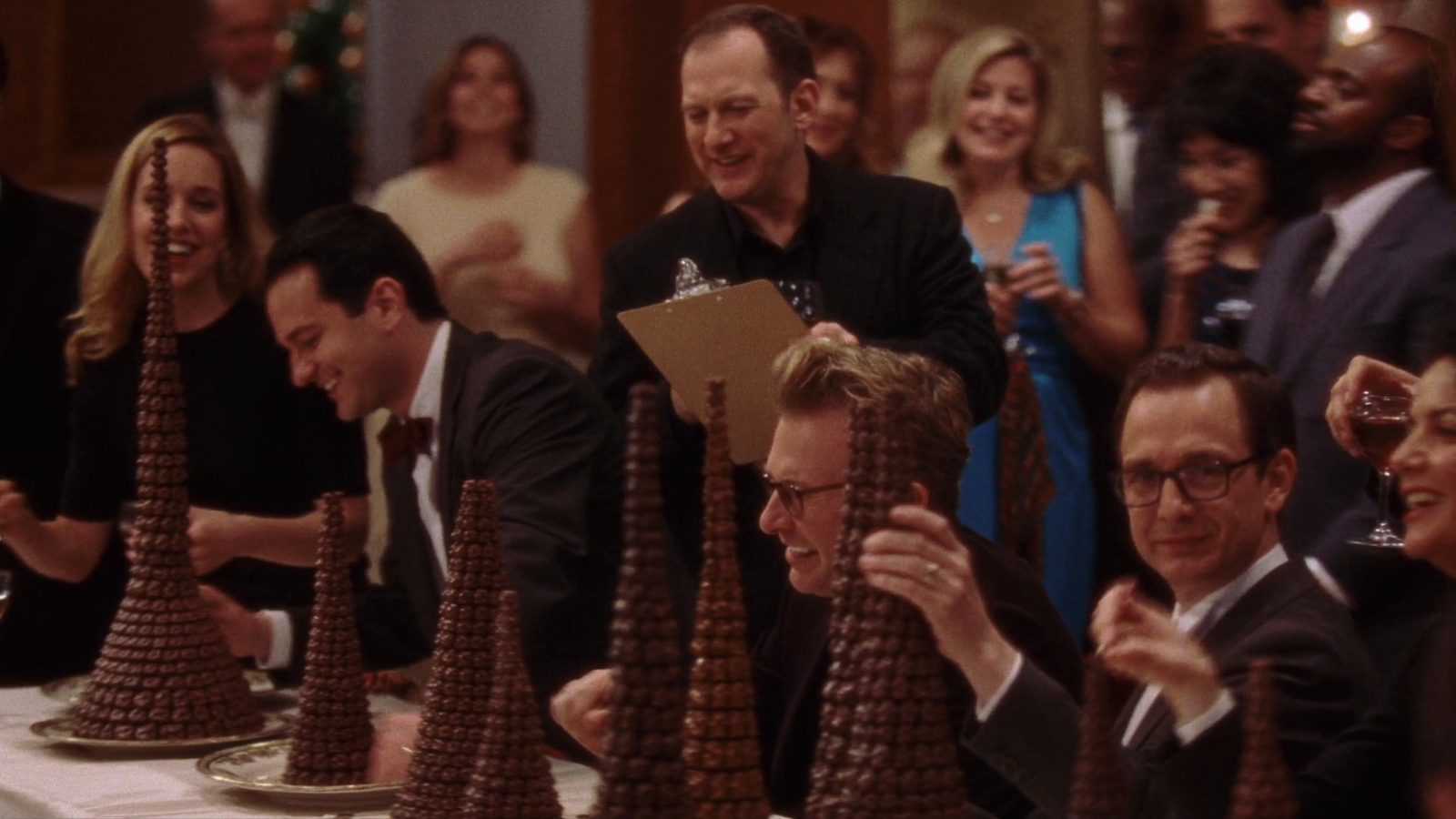 Teams building tall chocolate sculptures on long tables at a corporate event