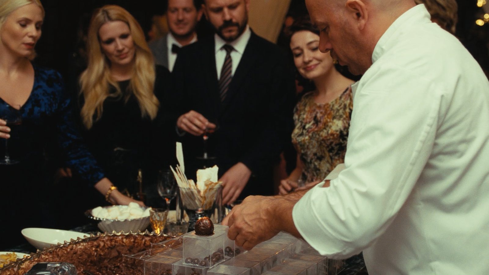 Chocolatier assembling hot chocolate bombs for guests at a holiday party station