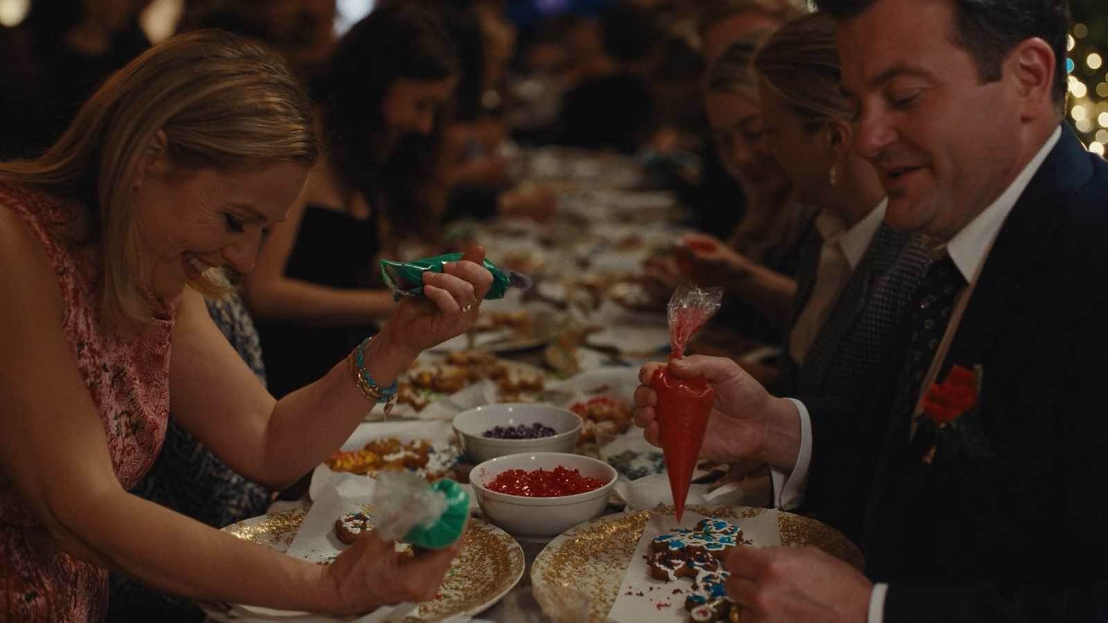 Guests decorating gingerbread and sugar cookies with icing and sprinkles at a long table