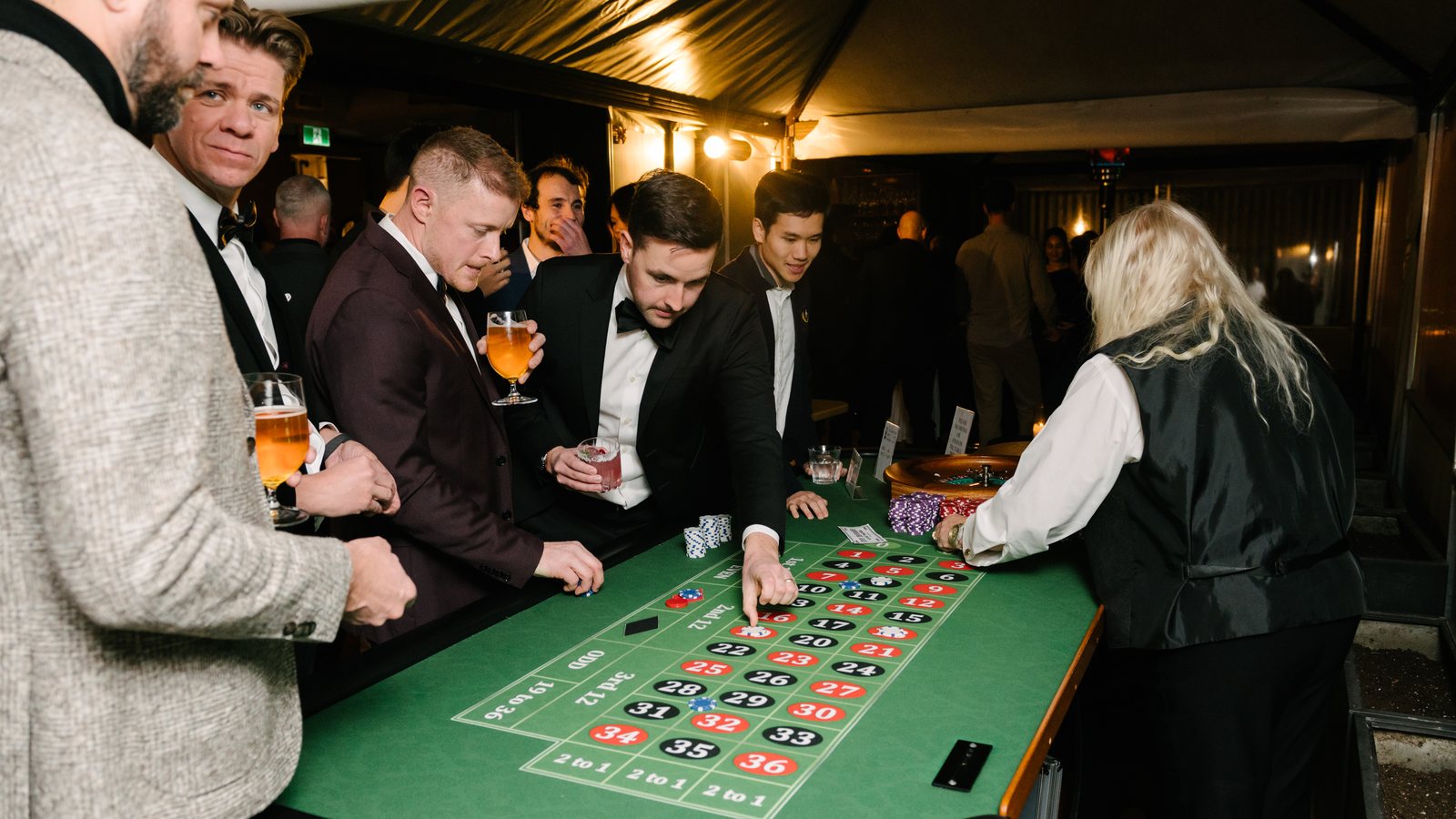Guests in evening wear placing bets at a roulette table during a corporate holiday party in Toronto