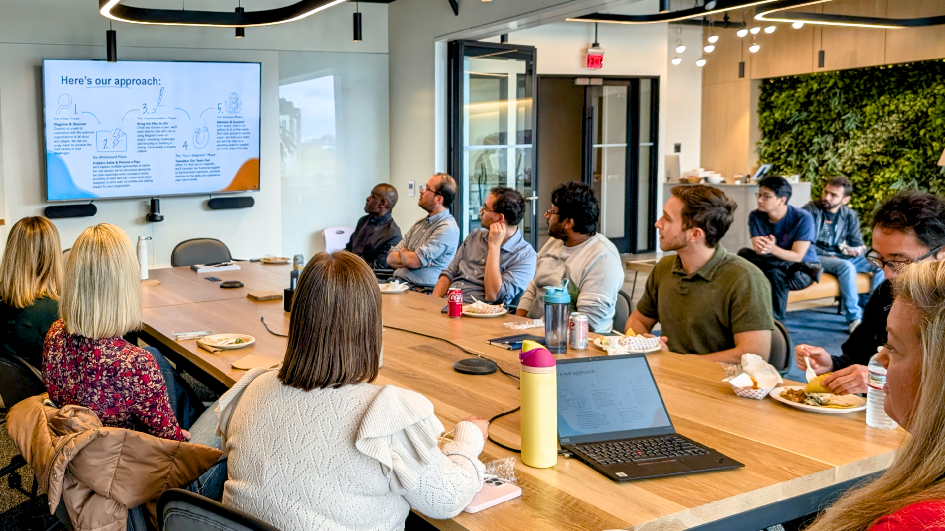 Conference room at Hatch.Bio Labs with a large table, presentation screen, and private team meeting areas