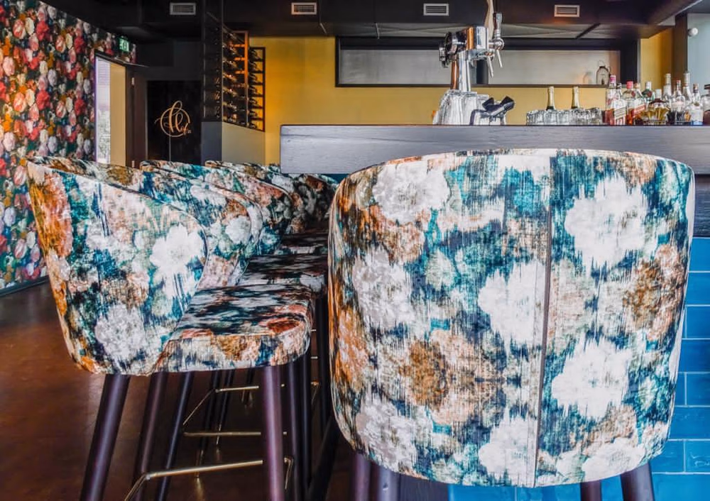 Bebloemde barstoelen aan een bar in een gezellig restaurant.
