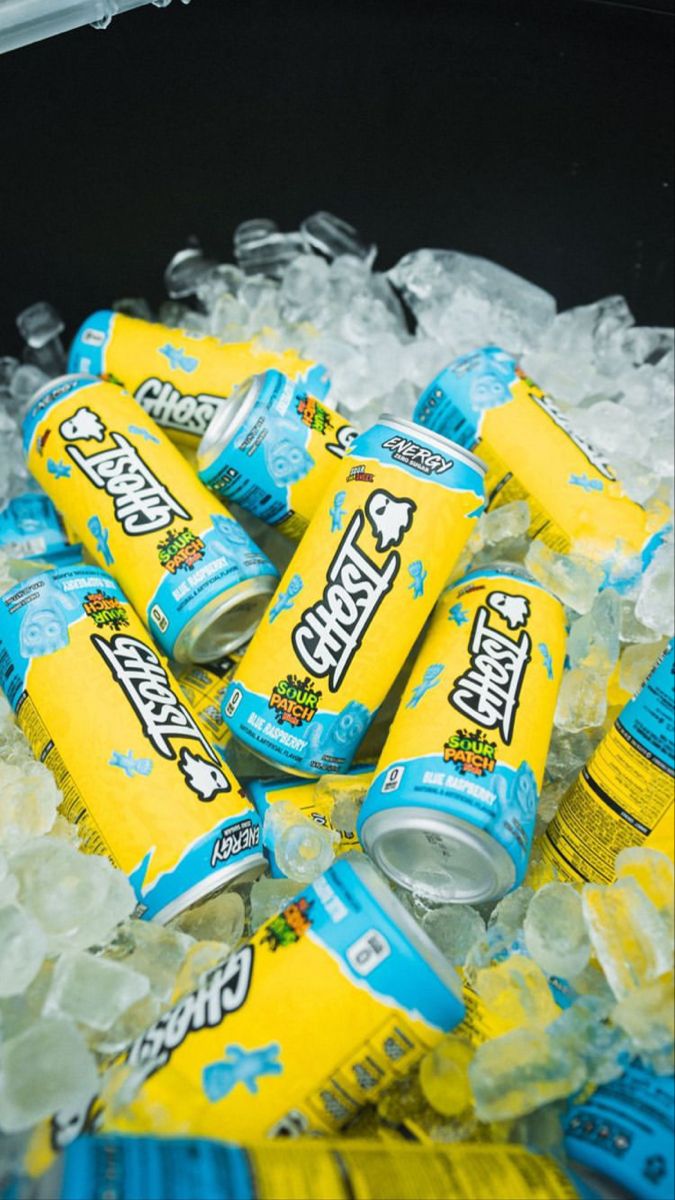 This may contain: a pile of blue and yellow sodas sitting on top of ice