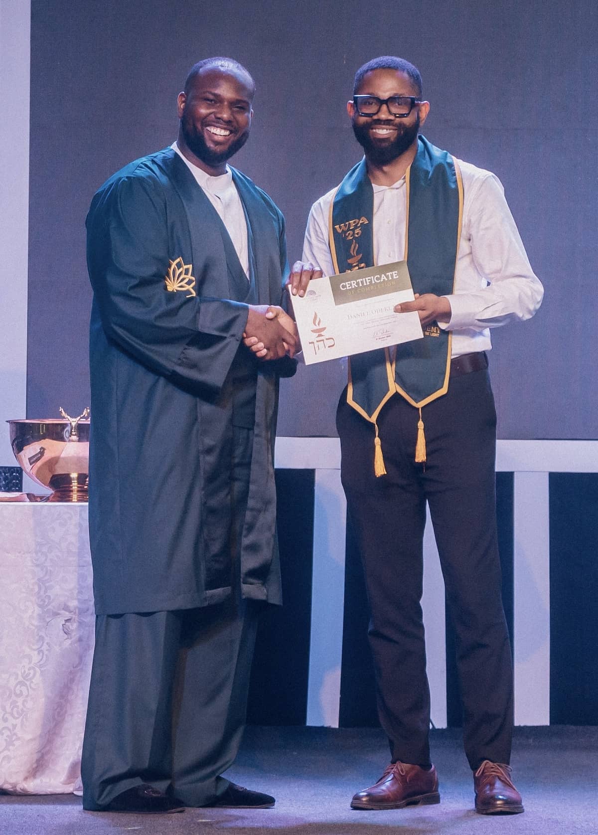 Portrait of a student receiving their certificate from our teacher at the graduation ceremony of the workplace altar