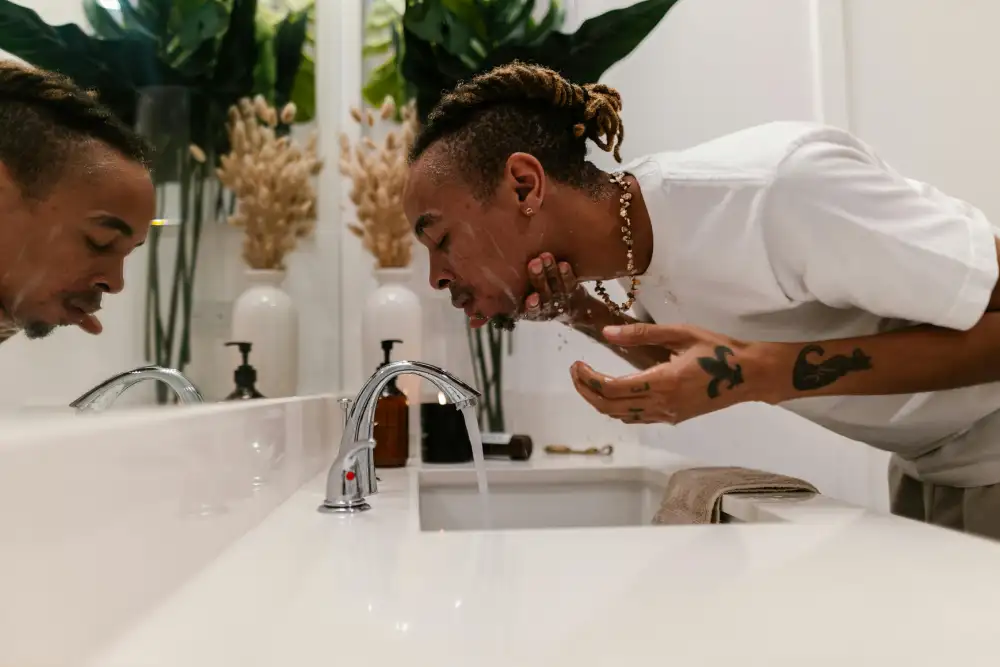 Man washing face at home to avoid acne.