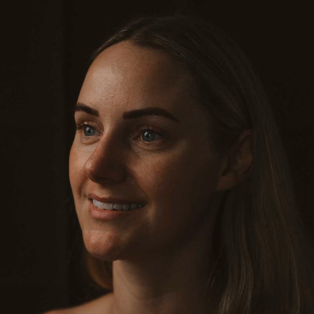 Portrait of a smiling person against a dark background.