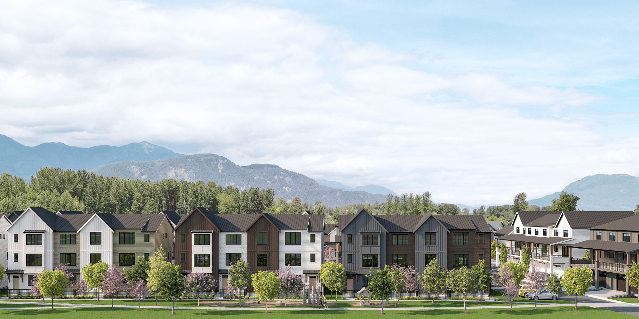 Chilliwack homes townhome row with green lawn, walking path and mountain backdrop.