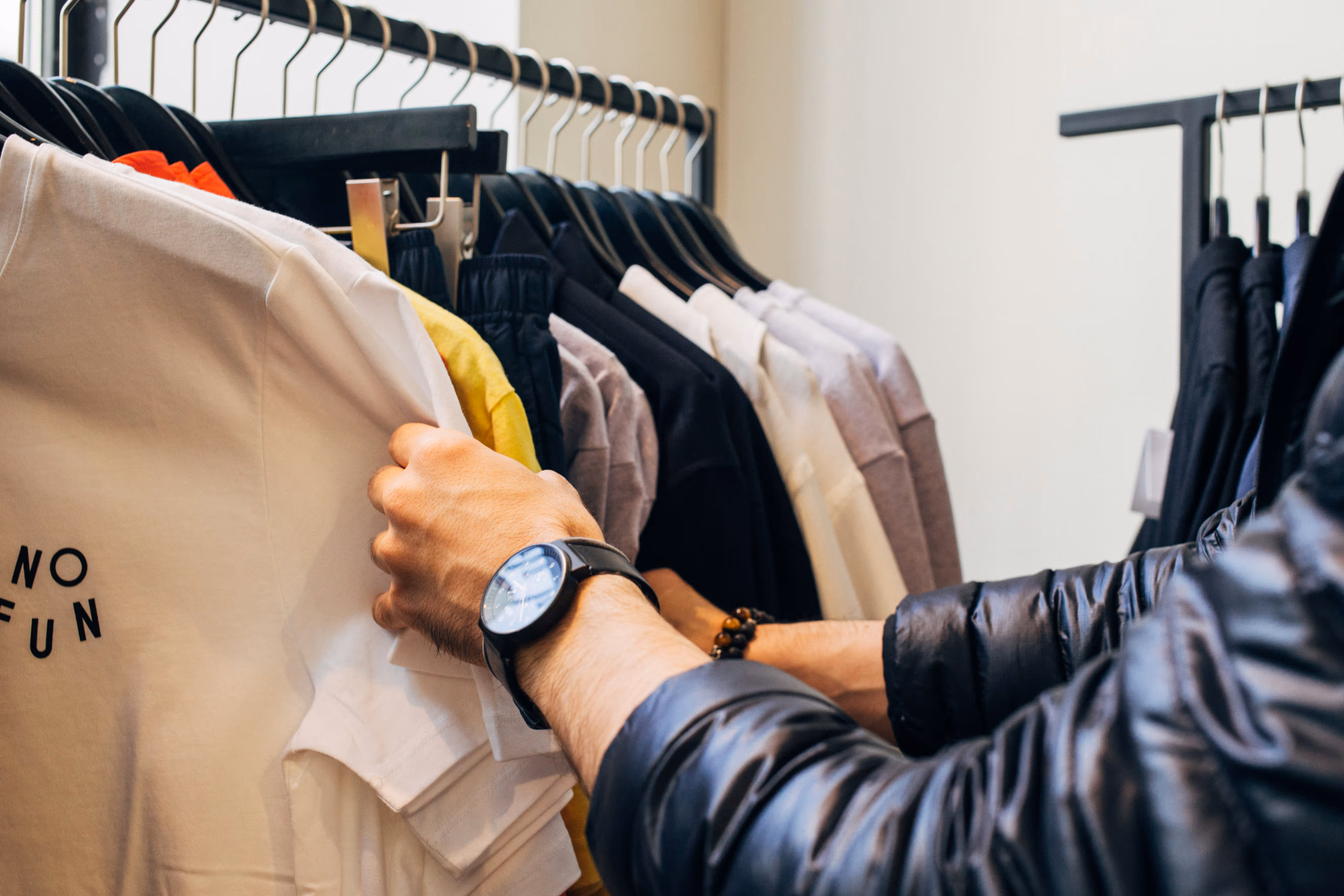 A customer browses a selection of trendy t-shirts in a retail store, showcasing various colours and styles. The image captures the essence of modern fashion shopping, highlighting clothing options for a stylish lifestyle.